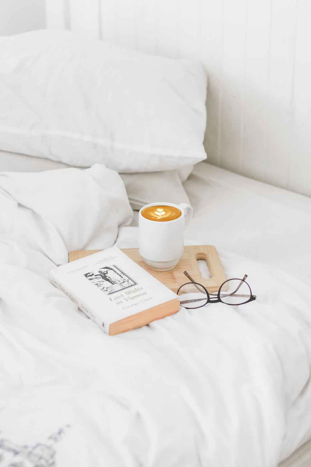 Cama minimal con sábanas blancas y cage barista