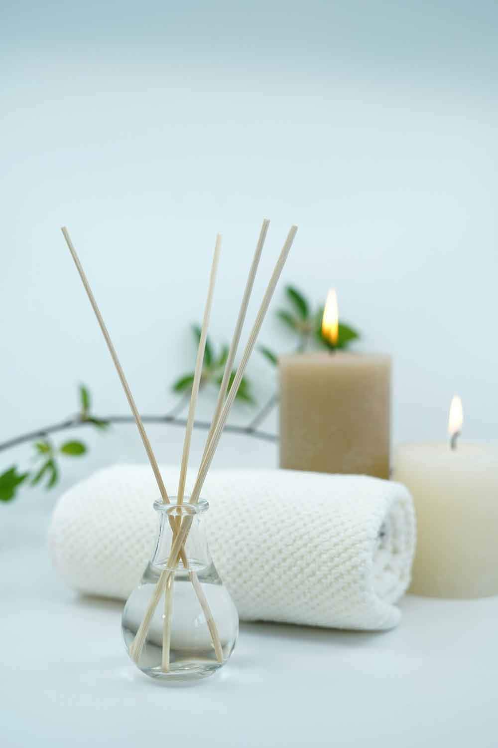 Decoración de spa con toalla doblada en rollo y ambientador de palitos