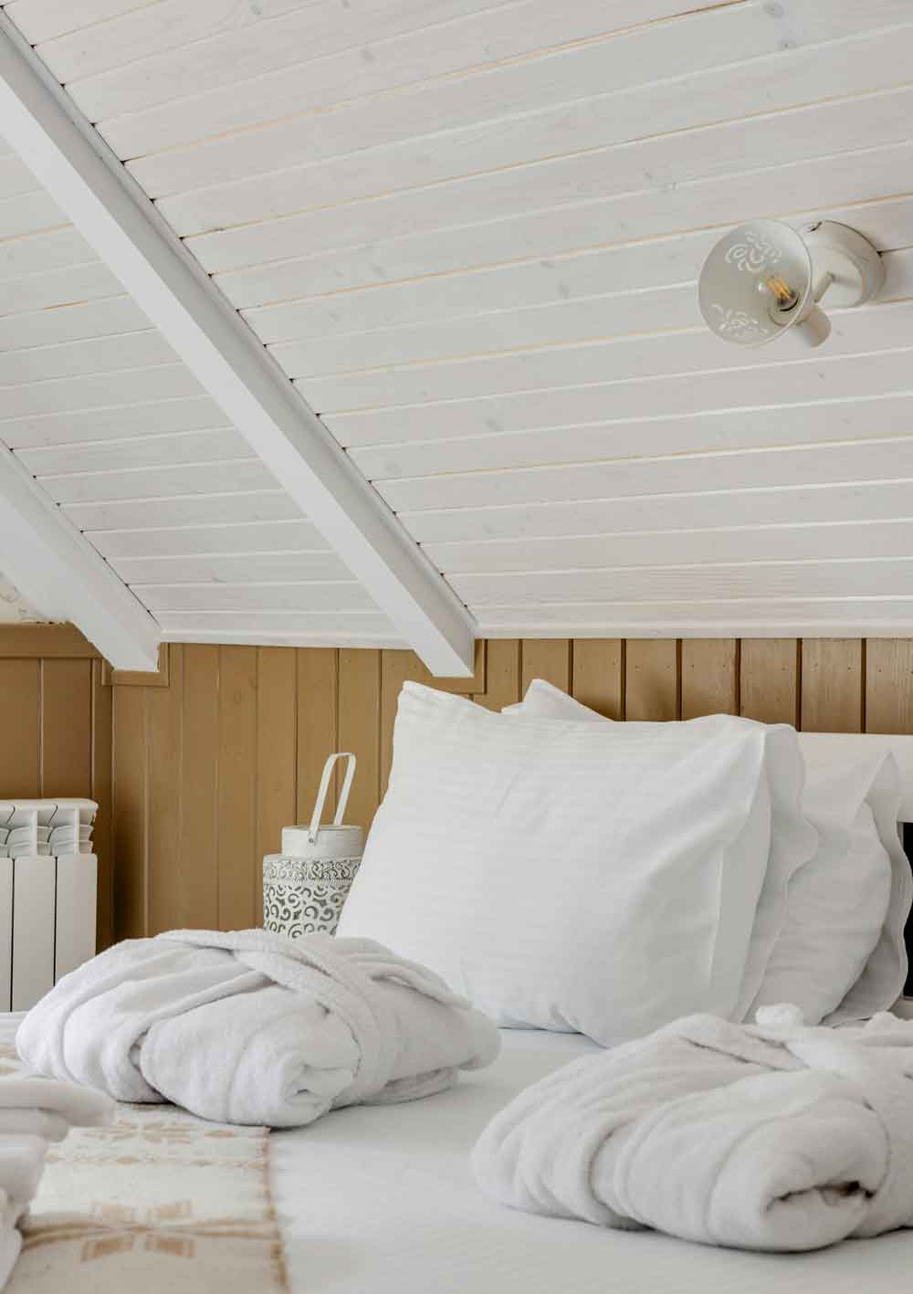 Habitación de casa rural con sábanas blancas y albornoses