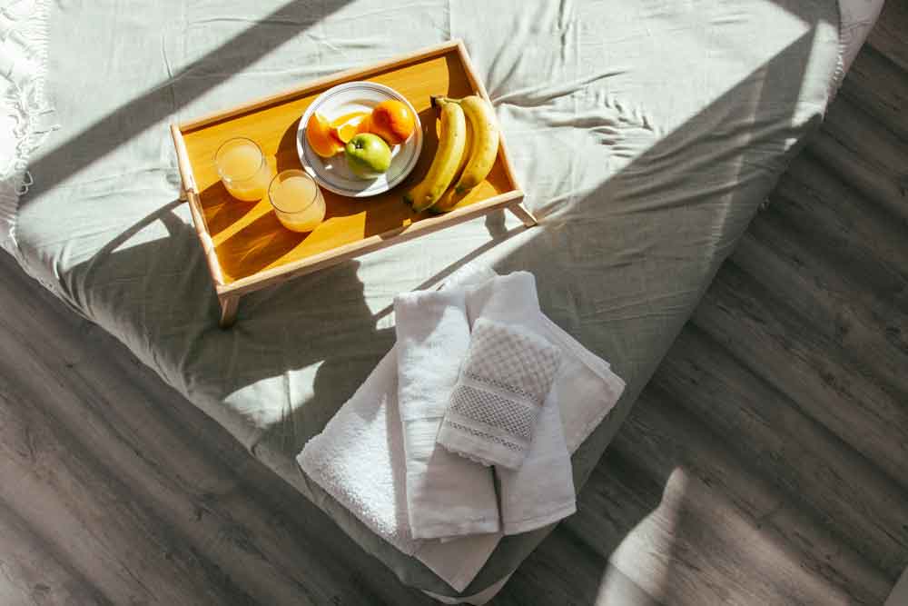 Cama con sabanas verdes de lino y juego de toallas dobladas estilo hotel