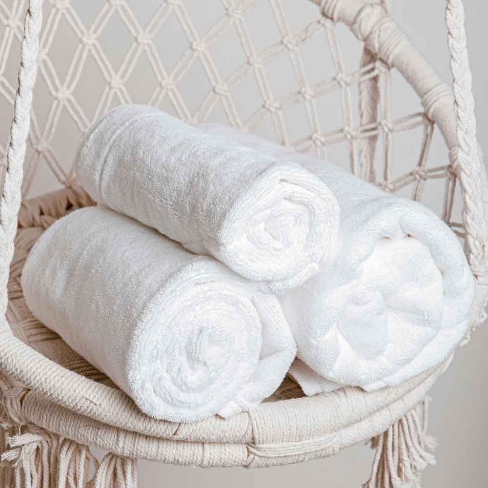 Tres toallas enrolladas sobre silla boho