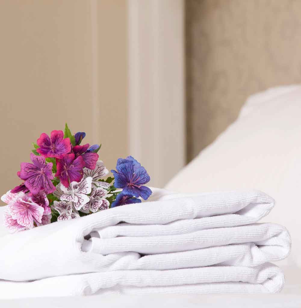 Cama de hotel con toallas blancas y decorado de flores